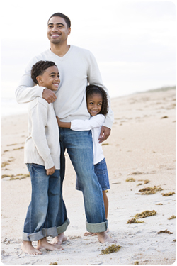 African-American father and two children on beach