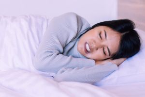 Young woman sleeping uncomfortably due to bruxism symptoms