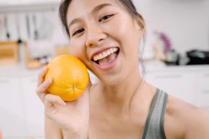 Smiling young woman holding an orange for a healthy snack